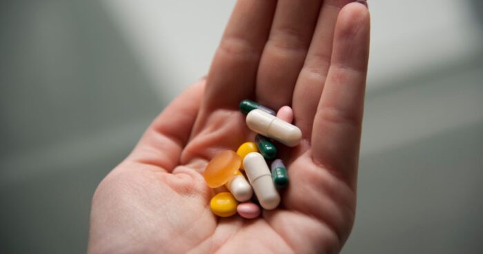 Drug allergy — Woman holding various pills in her hand and thinking about drug allergy.
